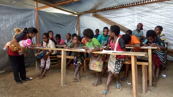 A teacher formerly posted in Nduga, holds her infant while instructing the children in the emergency school / Sorang Saragih