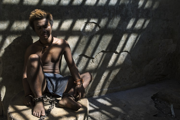 An inmate is shackled in unsanitary conditions at a social care institution. Central Java, 4 October 2018 ©2018 Andrea Star Reese